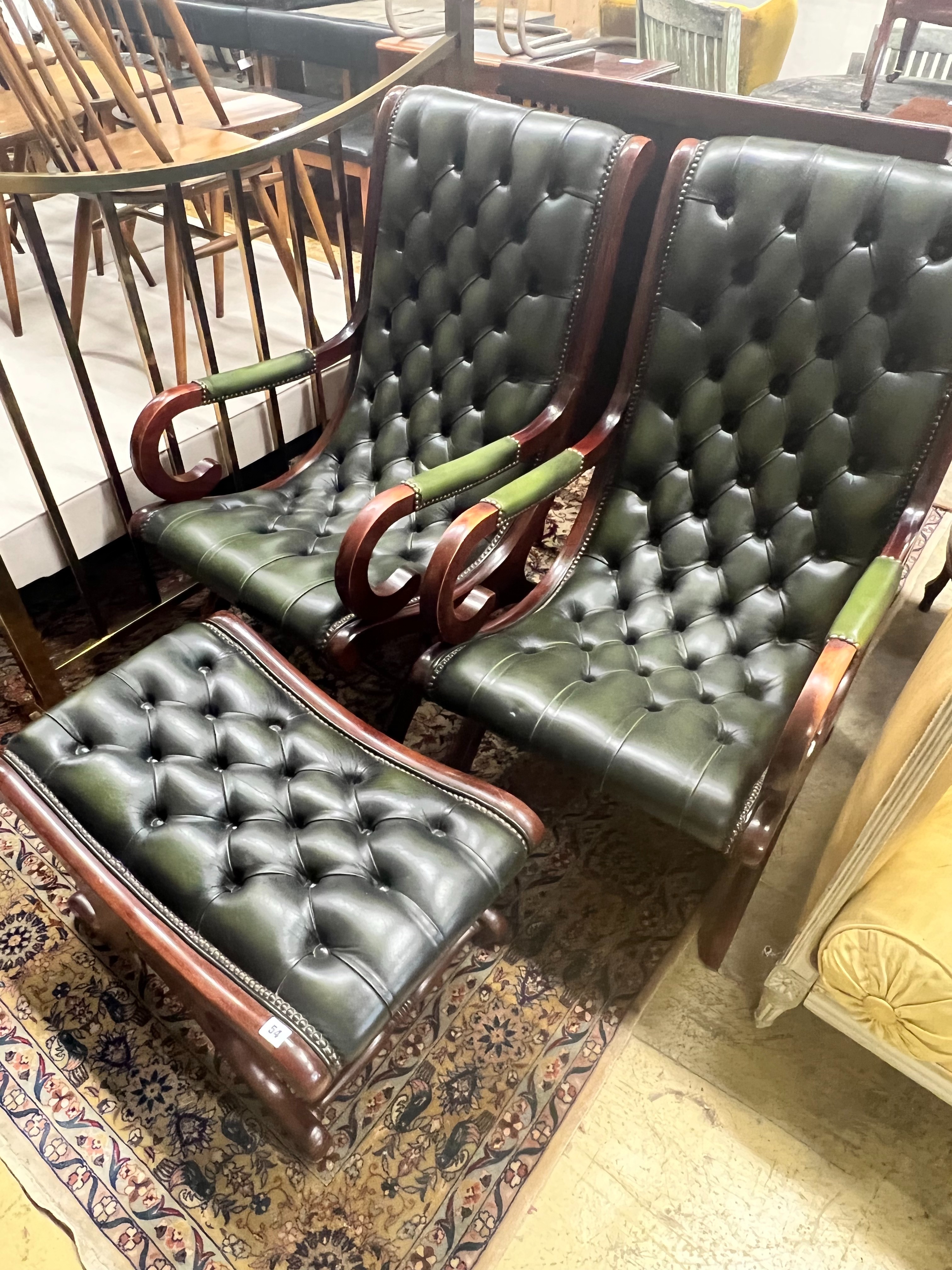 A pair of Victorian style mahogany and buttoned green leather open armchairs and matching footstool